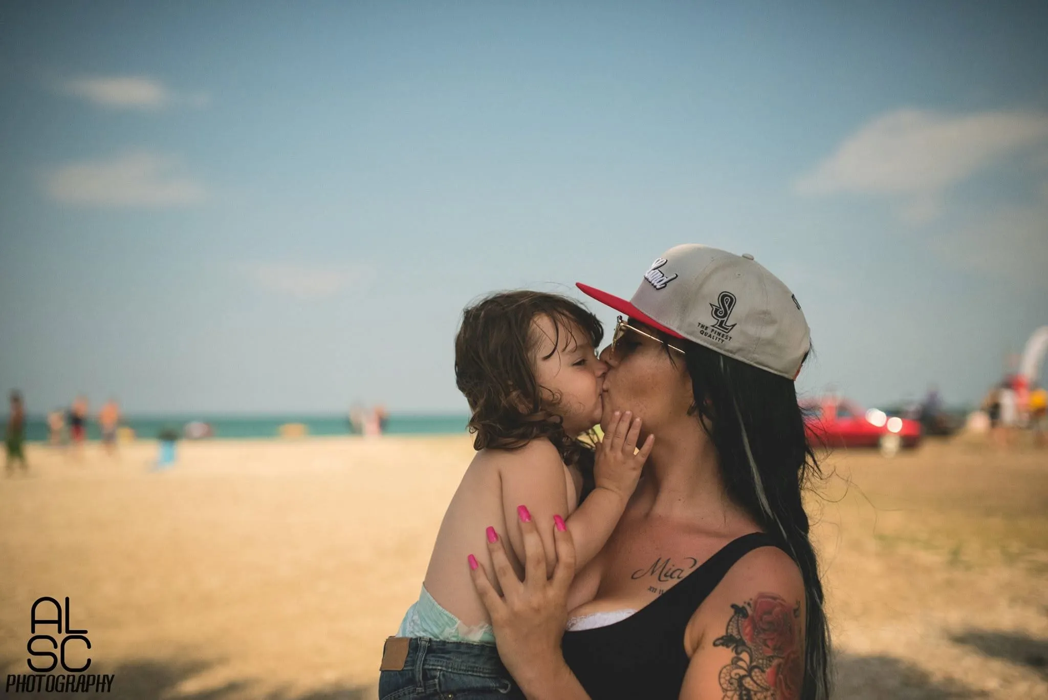 Due che si baciano sulla sabbia, a raduno aperto.