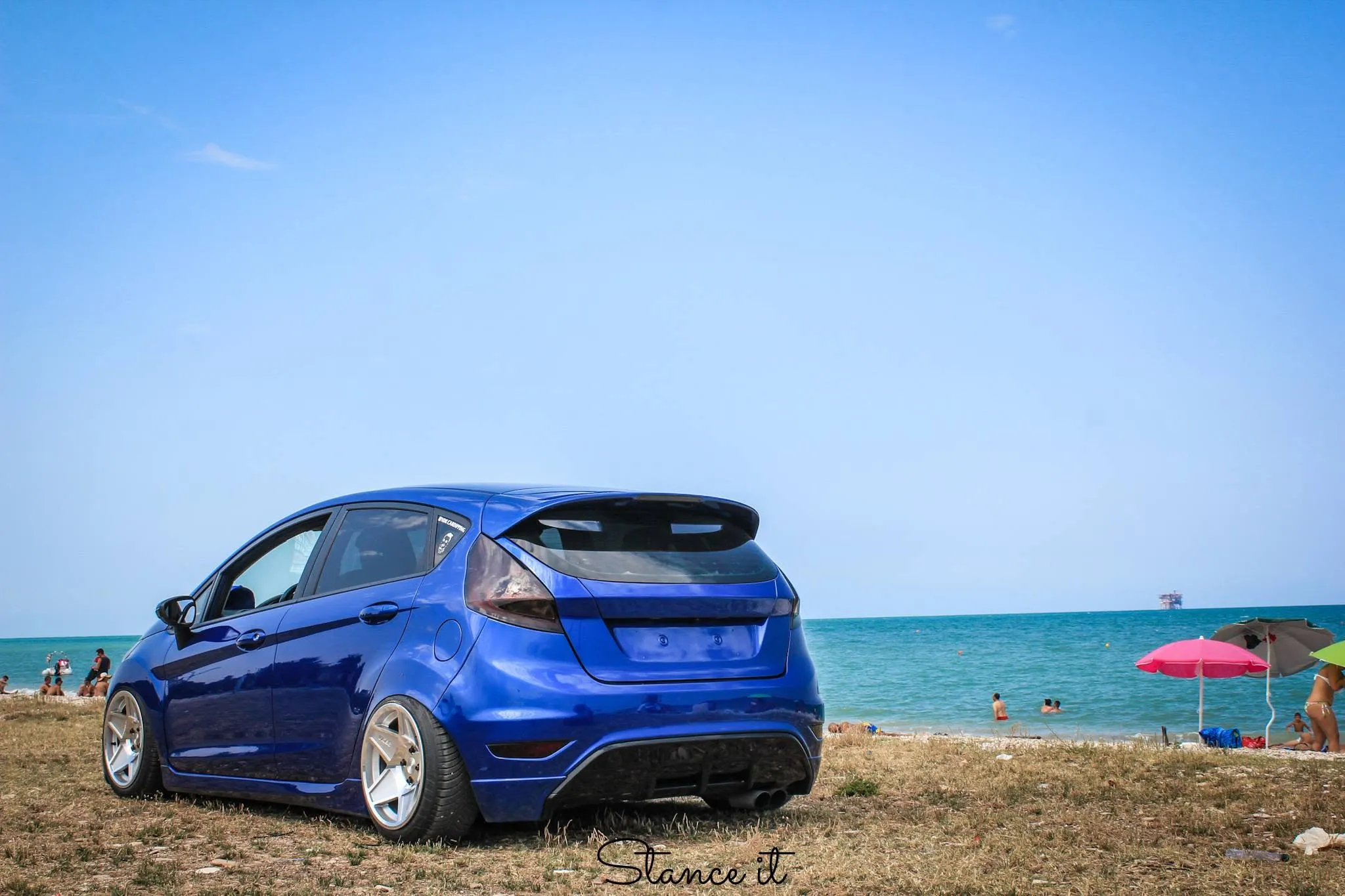 Blu elettrico a bordo spiaggia, con il mare dietro.
