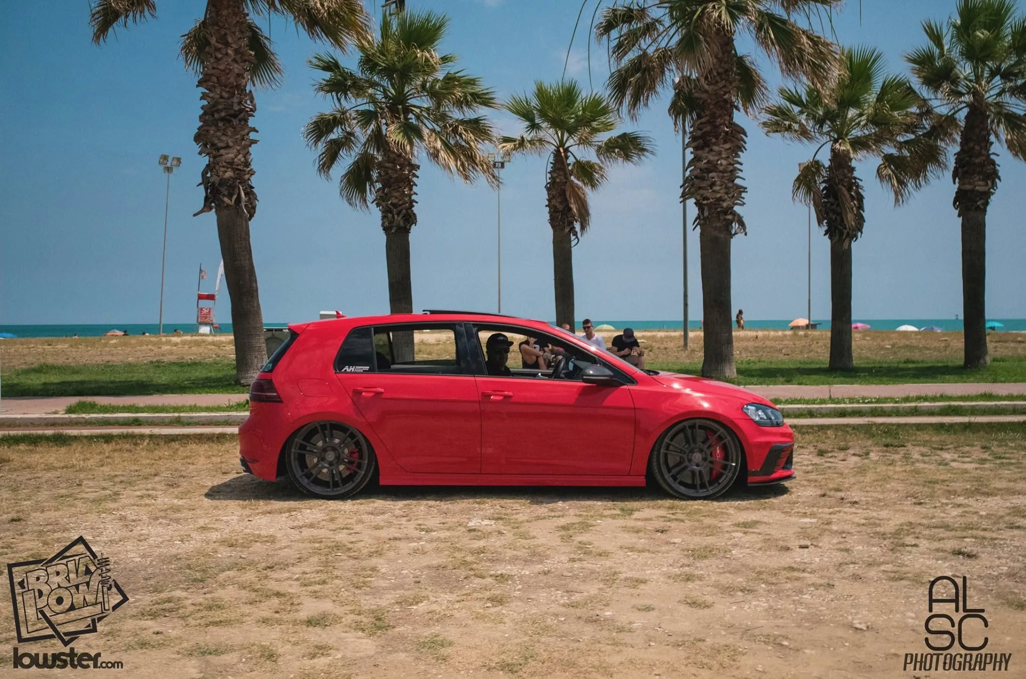 Una Golf rossa parcheggiata dove il prato incontra la spiaggia.