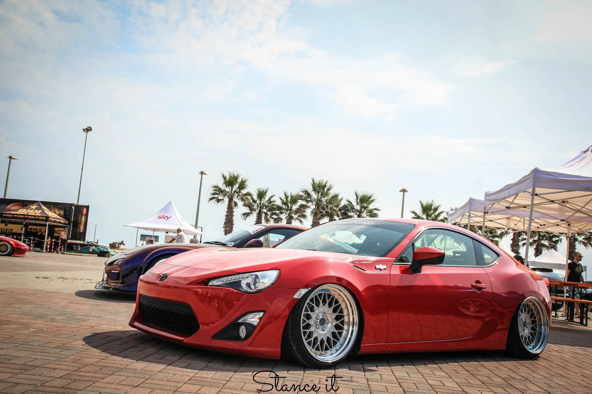 Una GT86 rossa a terra, sotto le palme.