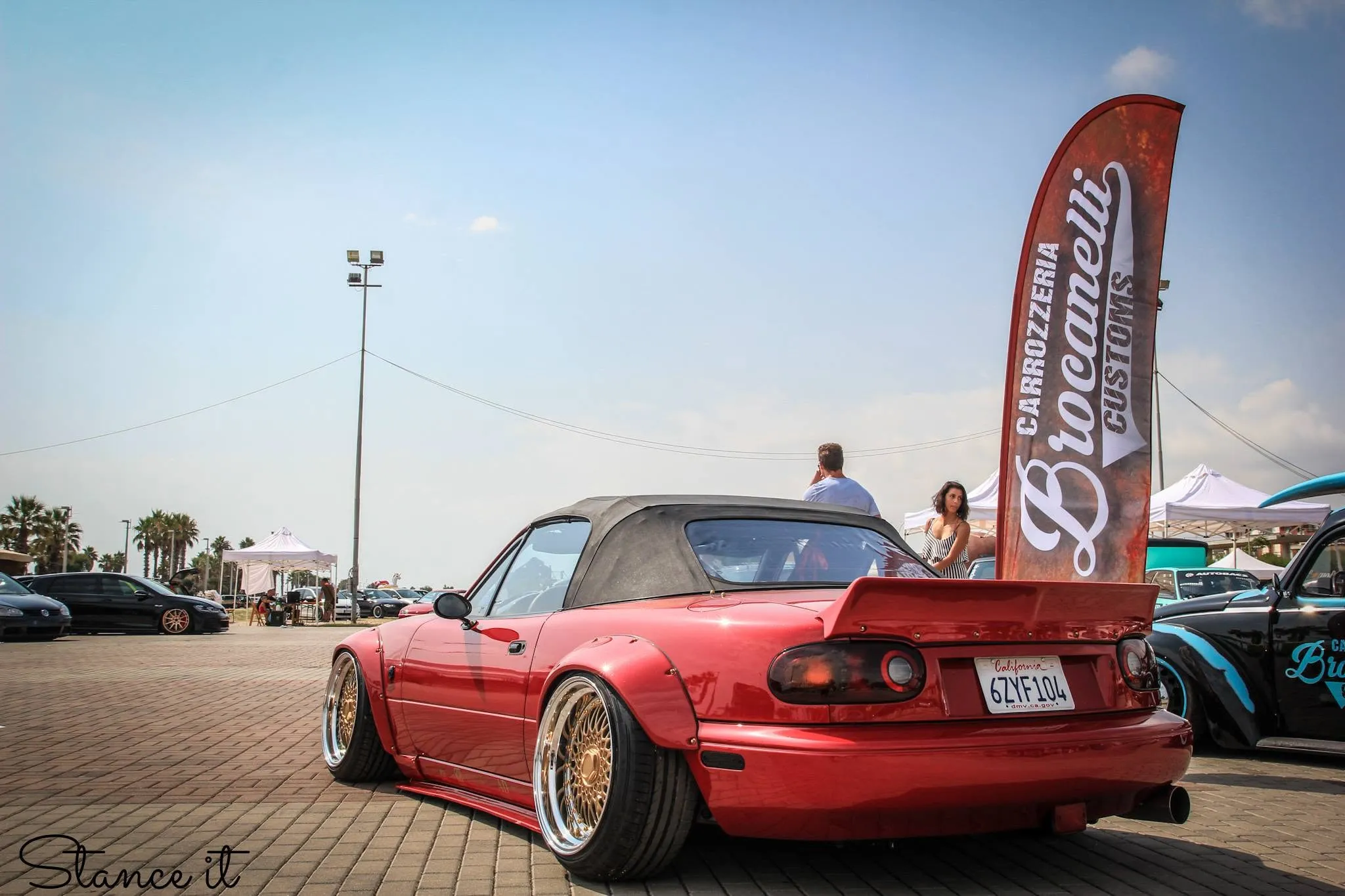 Una MX-5 rossa, il tetto giù e i cerchi dorati.